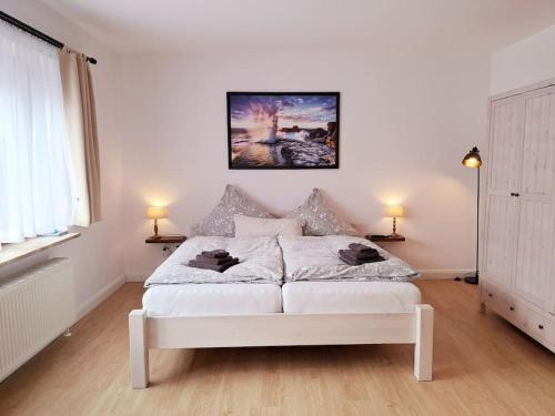 a white bed in a white room with two lamps at Ruhiges 1-Zimmer-Appartement, Büsum (4km), Nordsee in Oesterdeichstrich