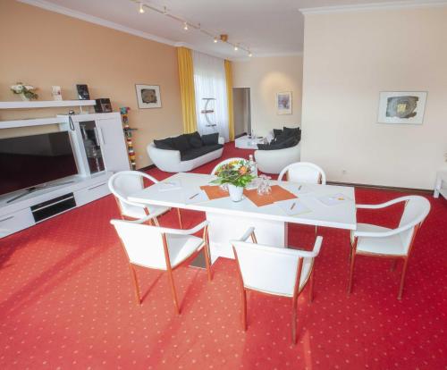 Hotel Hochsauerland 2010 في فيلنغن: غرفة معيشة مع طاولة وكراسي بيضاء