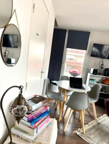 een woonkamer met een tafel en stoelen en een spiegel bij Aux charmes de Courbevoie in Courbevoie