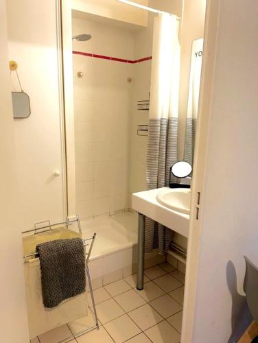 een badkamer met een douche, een wastafel en een bad bij Aux charmes de Courbevoie in Courbevoie