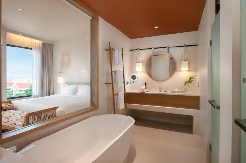 ein Bad mit einer Badewanne, einem Bett und einem Spiegel in der Unterkunft Centara Ayutthaya in Phra Nakhon Si Ayutthaya