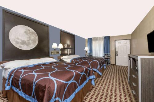 a hotel room with three beds and a television at Super 8 by Wyndham Houston Webster NASA in Webster