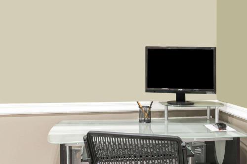 a computer monitor sitting on a desk with a chair at Super 8 by Wyndham Houston Webster NASA in Webster