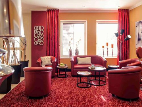 a living room with red chairs and tables at Mercure Hotel Ingolstadt in Ingolstadt