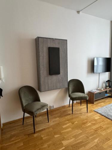 two chairs sitting in a living room with a tv at Studio apartment in Oslo