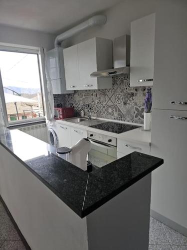 a kitchen with white cabinets and a black counter top at La Casa della Lavanda in Borgo Adorno