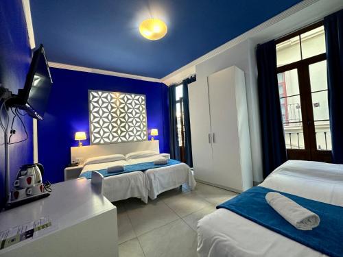 a blue room with two beds and a television at Nest Style Granada in Granada