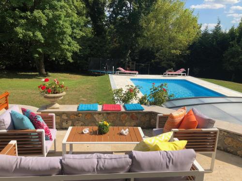 un patio avec une table et des chaises à côté d'une piscine dans l'établissement La Villa Martinière, à Bièvres