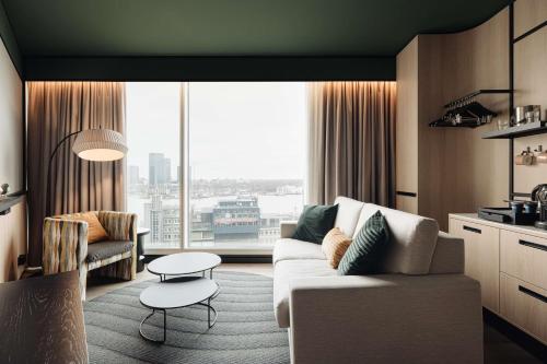 a living room with a couch and a large window at DoubleTree by Hilton Amsterdam Centraal Station in Amsterdam