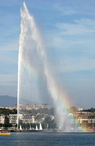 a large fountain in the water with a rainbow at Duplex à 2 pas de l'aéroport, proche ONU & Palexpo in Ferney-Voltaire