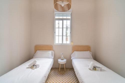 2 Einzelbetten in einem Zimmer mit Fenster in der Unterkunft Apartment Mosaic Giralda in Sevilla