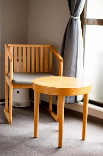 a wooden chair and a stool next to a window at Hotel Neiraku in Nara
