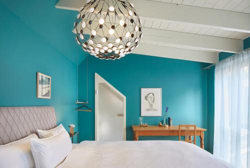 a blue bedroom with a bed and a chandelier at FriesThinkLand in Tönning