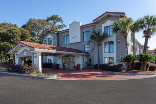 a large white building with palm trees in front of it at La Quinta Inn by Wyndham Pensacola in Pensacola