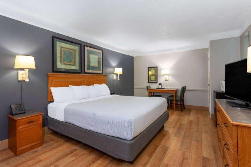 a hotel room with a bed and a flat screen tv at La Quinta Inn by Wyndham Pensacola in Pensacola