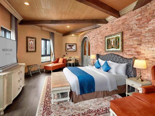 a bedroom with a large bed and a brick wall at Mercure Danang French Village Bana Hills in Danang
