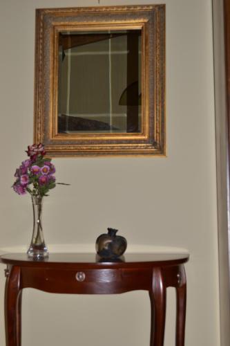 a vase of flowers on a table with a mirror at Pension Anapli in Nafplio