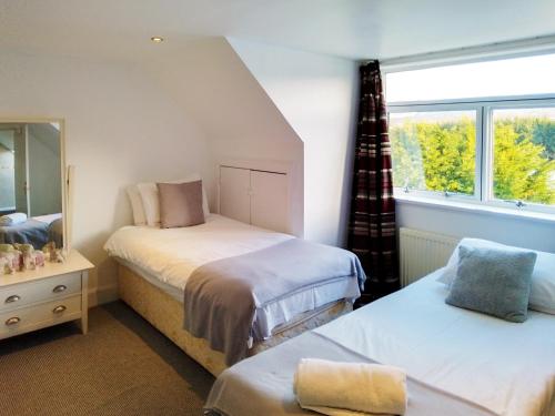 a small bedroom with two beds and a window at Colzium Farmhouse in Blitterlees
