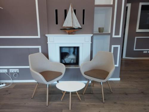 Amalien 12 في ميونخ: كرسيين وطاولة في غرفة بها موقد