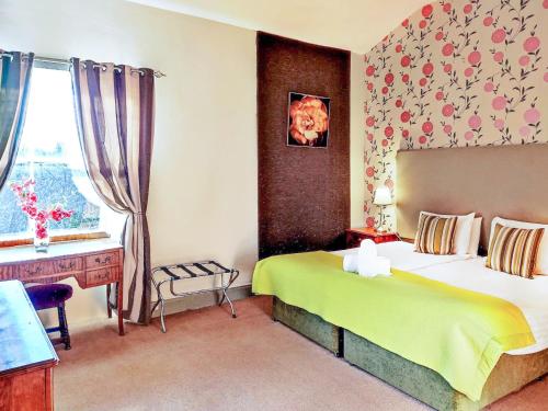 a bedroom with a bed and a desk and a window at The Mansion House At Kirkhill in Arniston