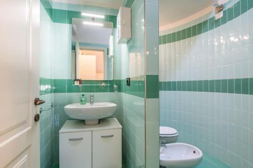 uma casa de banho com azulejos verdes, um lavatório e um WC. em Piazza Anfiteatro- elegant apartment em Lucca