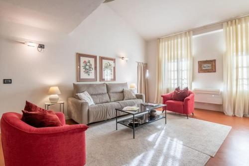 uma sala de estar com um sofá e duas cadeiras vermelhas em Piazza Anfiteatro- elegant apartment em Lucca