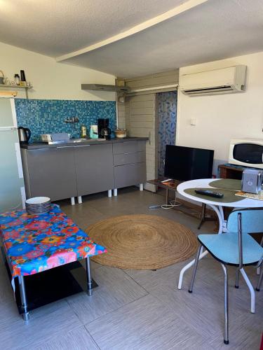ein Wohnzimmer mit einem Tisch und einer Küche in der Unterkunft Chalet des oliviers avec climatisation in Béziers