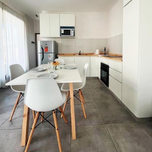 a kitchen with a white table and white chairs at Te veo bien in Suipacha