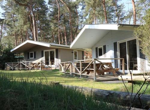 a small white house with a porch and a porch at Boslodge XL in Alphen