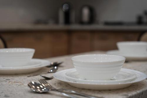 a table with white bowls and spoons and forks at KR Pokoje in Tokarnia