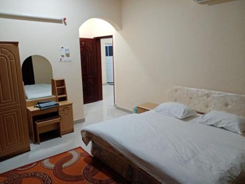 a bedroom with a bed and a dresser and a mirror at Luluat Al Afia Hotel Apartments in Sur