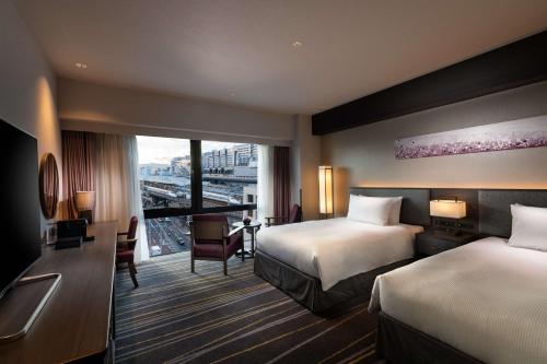 a hotel room with two beds and a window at DoubleTree by Hilton Kyoto Station in Kyoto