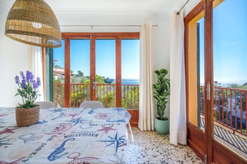 um quarto com uma mesa e uma varanda com janelas em Ses Savines Beach cala Llombards em Santanyí