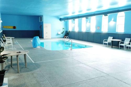 a swimming pool in a room with a table and chairs at Baymont by Wyndham Iron Mountain in Iron Mountain