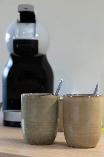 two cups sitting on a counter with a coffee maker at B & B De Romeinse Katzei in Borgloon
