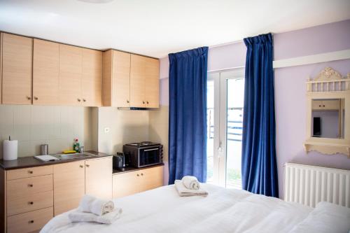 a bedroom with a bed and a kitchen with blue curtains at Aesthetic Studio in Patra