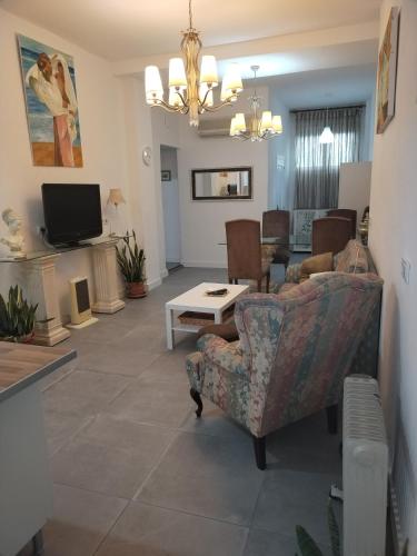 a living room with a couch and chairs and a tv at Casa Tagore in Utrera