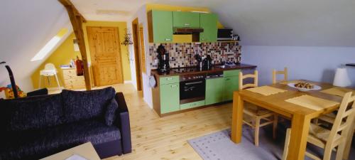 cocina con armarios verdes, mesa y sofá en Ferienhof Bauer, en Gotthun