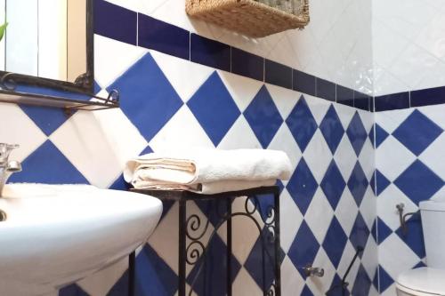 uma casa de banho com lavatório e azulejos azuis e brancos em Riad Elaissi em Tarudante