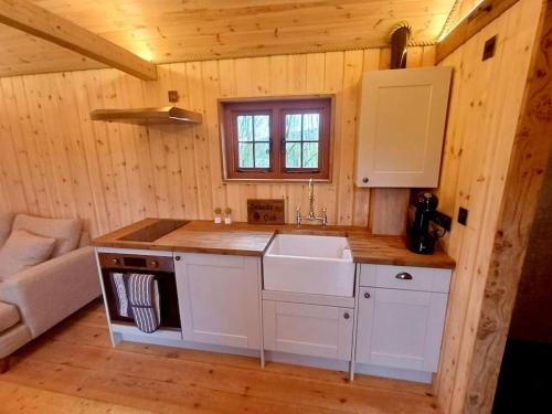a kitchen with white cabinets and a sink in a cabin at Shepherds Hut/Hot Tub Private Lake Jurassic Coast in Bridport