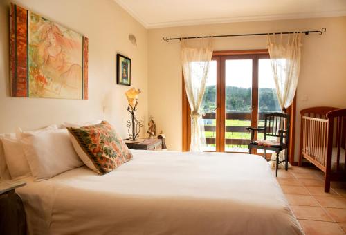 Un dormitorio con una gran cama blanca y una ventana en Olival House en Paço de Sousa