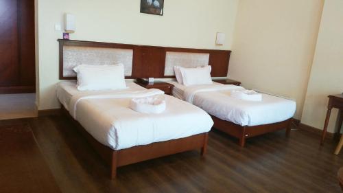 a hotel room with two beds with white sheets at Zhingkham Guest Houses in Thimphu