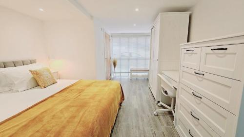 een witte slaapkamer met een bed en een bureau bij Oakdale at Weavers Yard in Farnham