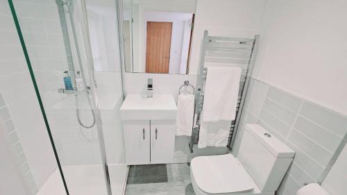 een witte badkamer met een toilet en een wastafel bij Oakdale at Weavers Yard in Farnham