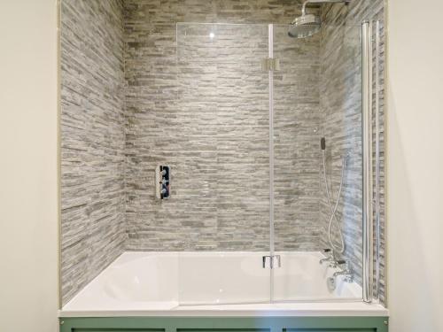 uma banheira branca numa casa de banho com uma parede de tijolos em 2 Pheasant em East Ilsley