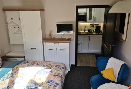 ツィングストにあるZimmer " Sonnenschein"のベッド1台、椅子、キッチンが備わる客室です。