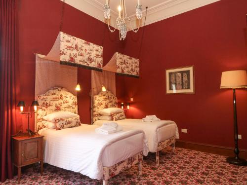 two beds in a room with red walls at Derry - Mar Lodge Estate in Ballater