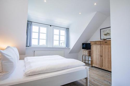 a white bedroom with a bed and a window at Haus Wattpieper in Munkmarsch