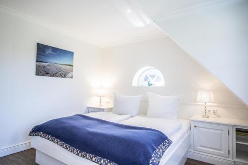 a white bedroom with a blue blanket on a bed at Haus Twesk Merre in Munkmarsch