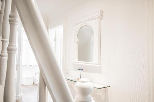 a white hallway with a mirror and a staircase at Haus Twesk Merre in Munkmarsch